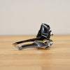 A Shimano Ultegra bicycle derailleur in black and silver, resting on a light wooden tabletop against a neutral beige background.
