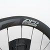 Close-up of a dark gray Zipp 303 firecrest carbon fiber bicycle wheel rim with the brand logo clearly visible against a light gray background.