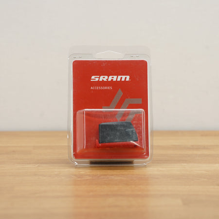 SRAM battery in a clear blister pack with a red backing card, placed on a light wooden surface against a plain light gray wall.