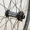 A close up photo of a black DT swiss front hub with white letters against a plain white wall. 
