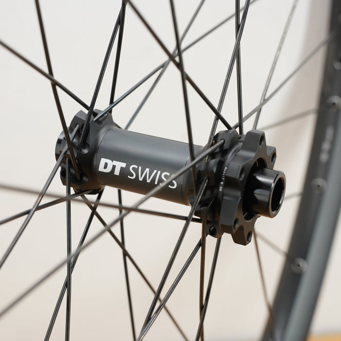 A close up photo of a black DT swiss front hub with white letters against a plain white wall. 