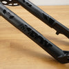 Close-up of a black Fox mountain bike front fork, resting on a light wood floor.