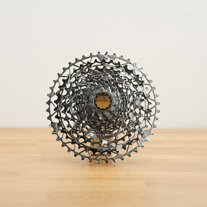 A silver SRAM Rival cassette photographed on a light wooden surface against a plain white backdrop.