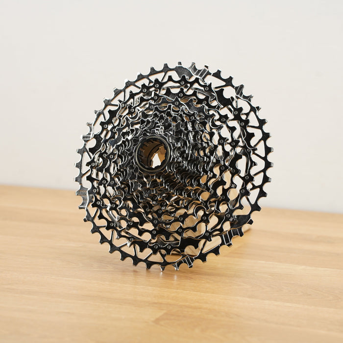 A silver SRAM Rival cassette photographed on a light wooden surface against a plain white backdrop.