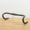 A dark grey Parlee branded carbon road bike handlebar photographed on a light brown wooden surface against a plain white background.