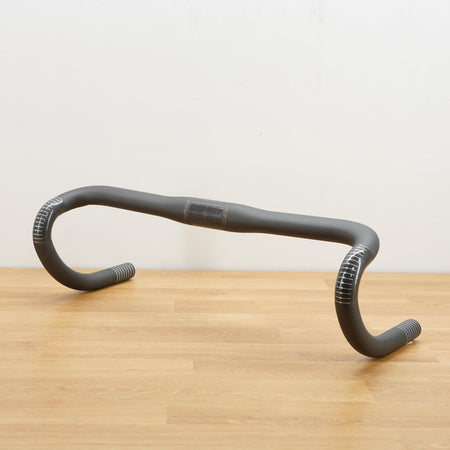 A dark grey Parlee branded carbon road bike handlebar photographed on a light brown wooden surface against a plain white background.
